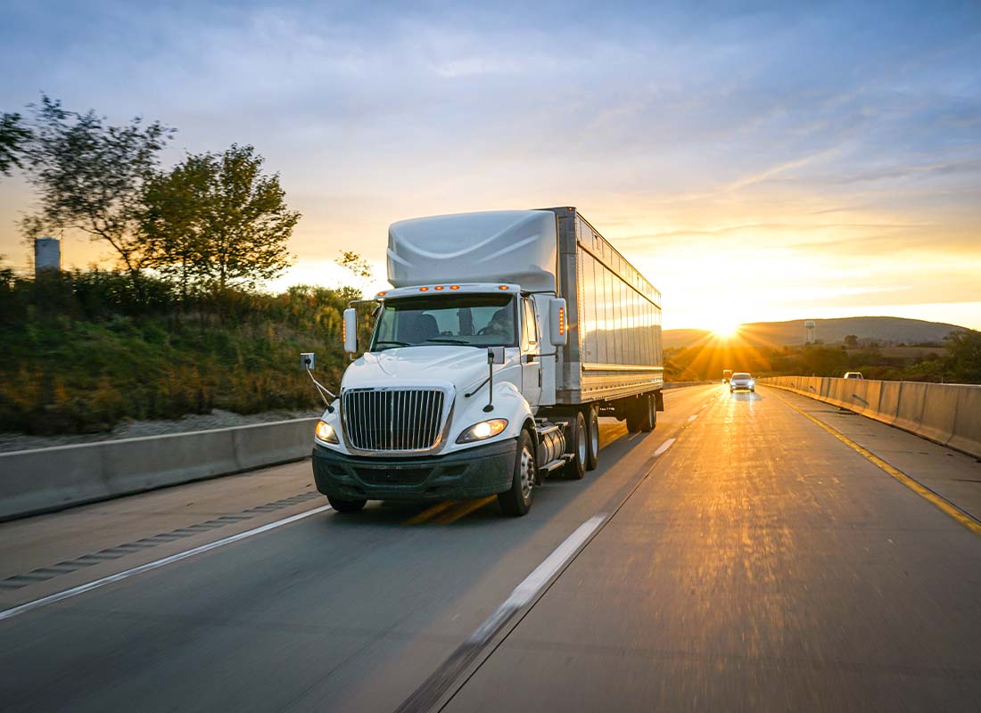 Inland Marine Insurance - White Semi-truck Transporting Cargo on the Highway and Delivering Freight across Country at Sunset